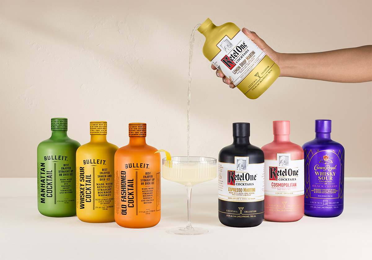 Tanqueray Negroni, Astral Margarita, Ketel One Cosmopolitan, Bulleit Manhattan, and Bulleit Old Fashioned pre-mixed cocktails sitting on a pink tiled table. There is a hand pouring a Ketel One Espresso Martini pre-mixed cocktail into a martini glass.