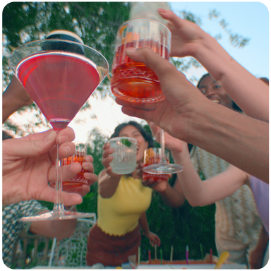 Seven people holding different cocktails up including a Ketel One Cosmopolitan, Astral Margarita, Ketel One Espresso Martini, and a Tanqueray Negroni.